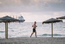 Homem velho forte faz exercício na praia — Fotografia de Stock