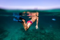 Неузнаваемый мальчик плавает с маской в морской воде — стоковое фото