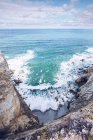Удивительный вид на морскую воду, плещущуюся рядом с длинной скальной скалой в пасмурный день в Астурии, Испания — стоковое фото