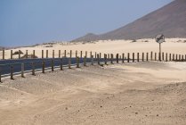 Carretera con señal y montañas en el desierto de Fuerteventura, Islas Canarias - foto de stock
