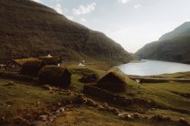 Камінь сільських будинків трава на дахах на схилі пагорба біля озера на Feroe острови — стокове фото
