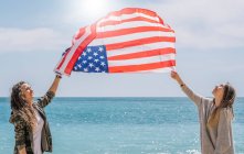 Duas meninas posando na praia com bandeira EUA. — Fotografia de Stock