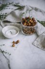Roasted chickpeas in glass jar on white marble surface — Stock Photo