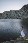 Elegante donna su abito bianco in piedi vicino lago increspatura — Foto stock