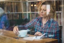 Mulher sentada no café e escrevendo em caderno — Fotografia de Stock