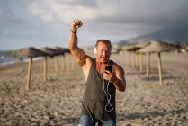 Älterer Mann hört Musik am Strand — Stockfoto