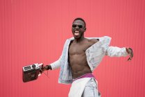 Homem americano africano dançando com dispositivo de rádio vintage em fundo vermelho — Fotografia de Stock