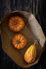 Halloween decoration of pumpkins in paper bag on dark background with copy space. — Stock Photo