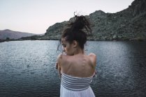 Junge Frau in elegantem Kleid steht am plätschernden See — Stockfoto