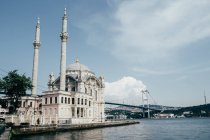 Magnífica vista de la hermosa mezquita de pie cerca de aguas tranquilas en el día nublado en Estambul, Turquía - foto de stock