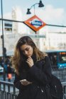 Donna che utilizza smartphone vicino alla metropolitana in città — Foto stock