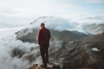 Escursionista in piedi sul bordo della montagna e guardando la vista sulle isole Feroe — Foto stock