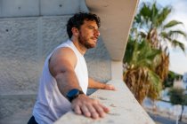 Retrato de homem desportivo pensativo em pé na varanda na praia — Fotografia de Stock