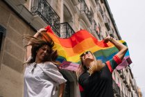 Пара лесбійок з гей-прайд прапором на вулиці Мадрида — стокове фото