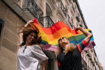 Casal lésbicas mulher com gay orgulho bandeira no o rua de madri cidade — Fotografia de Stock