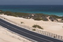 Straße durch Wüste und Ozeanwasser auf Kanarischen Inseln — Stockfoto