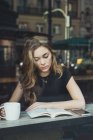 Junge blonde Frau liest Buch im Café — Stockfoto