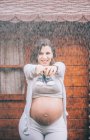 Beautiful pregnant woman posing in the rain — Stock Photo