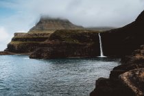 Мальовничий вид з прибережних скель і обприскування водоспад на Feroe острови — стокове фото