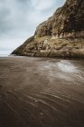 Playa y acantilado rocoso en el océano tranquilo en las Islas Feroe - foto de stock