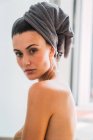Ritratto di giovane donna in topless con asciugamano sulla testa che si gira e guarda la macchina fotografica — Foto stock