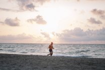 Сильный старик делает упражнения на пляже — стоковое фото