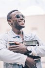 Sorrindo homem negro em óculos de sol segurando dispositivo de rádio vintage — Fotografia de Stock