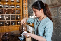 Giovane donna asiatica versando acqua dalla pentola mentre fa il tè sulla cerimonia tradizionale — Foto stock