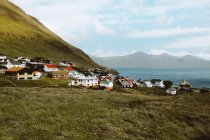 Vue sur petit village avec maisons colorées et montagnes verdoyantes sur les îles Feroe — Photo de stock