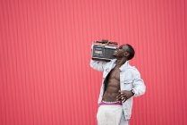 Uomo afroamericano sorridente con dispositivo radio vintage su sfondo rosso — Foto stock