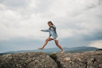 Жінка стрибає над тріщинами на каменях — стокове фото