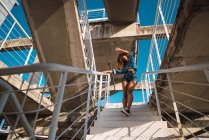 Young African American woman in denim clothes going down on metal staircase on street at daylight — Stock Photo