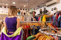 Schöner Mann wählt stylisches Hemd, während er Zeit in kleinem Geschäft mit Freundin verbringt — Stockfoto