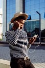 Homem preto em fones de ouvido usando smartphone — Fotografia de Stock