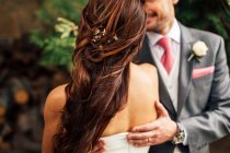 Hand of unrecognizable groom embracing bride in white dress. — Stock Photo