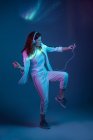 Woman dancing with smartphone and headphones in neon light — Stock Photo