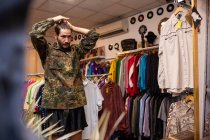 Fröhlicher Mann wählt Kleidung und Accessoires im Geschäft — Stockfoto