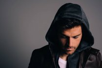 Junge attraktive brünette Mann trägt einen Kapuzenpullover in einem Studio — Stockfoto