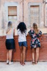 Three girls posing with their backs on the street — Stock Photo
