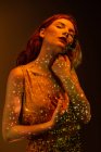 Femme élégante sensuelle posant dans la lumière chaude dans la chambre noire — Photo de stock