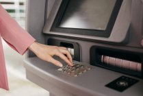 Weibliche Hand gibt PIN-Code in Geldautomat ein, der mit Kreditkarte arbeitet — Stockfoto