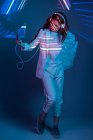 Woman in headphones looking at projection of neon light — Stock Photo