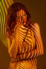 Portrait of dreamy woman in stripes of warm light — Stock Photo