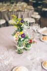 Brilhante belas flores rústicas em garrafa na mesa de banquete servida. — Fotografia de Stock
