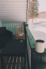 Vista exterior da varanda da casa de madeira com xícara de café na cerca e paisagem nevada no fundo — Fotografia de Stock