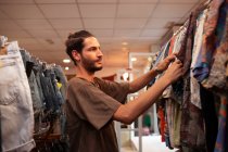 Веселый человек выбирает одежду и аксессуары в магазине — стоковое фото
