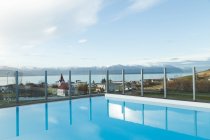 Paesaggio di acqua blu in piscina con lago e montagne sullo sfondo con la luce del sole sopra la piccola città sulla riva — Foto stock