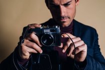 Молодий чоловік в студії тримає старовинну камеру — стокове фото
