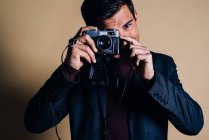 Young man in a studio holding a vintage camera — Stock Photo