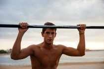 Junger Mann trainiert außen am Barren — Stockfoto